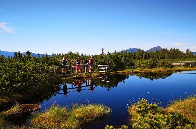 A still alpine pond on the high pastures, forest and a mountain ridge behind