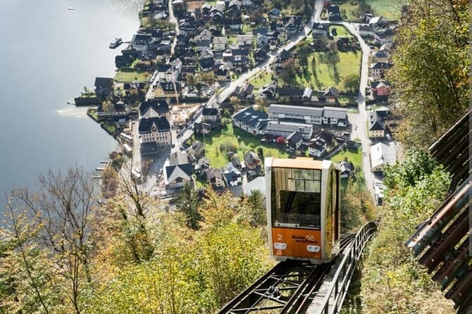 A funicular car climbing through the trees above the village roofs