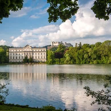 A pale lakeside palace behind still water and trees, near Salzburg