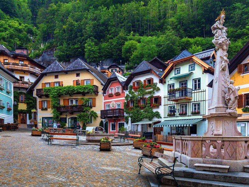 Painted houses and a stone column on the village square, mountains behind