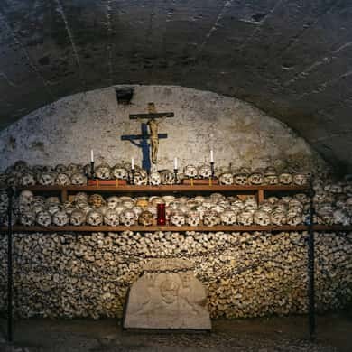 Rows of painted skulls stacked under a crucifix in the charnel house