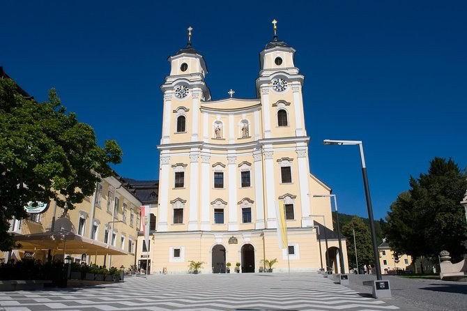 A twin-towered yellow basilica on a small town square