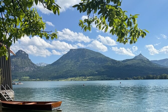 A wooden boat moored on a lakeshore under wooded mountains